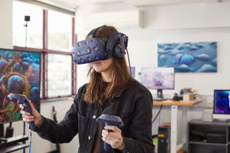 Student using virtual reality headset and controls in 3D Visualisation Aesthetics Lab.