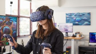 Student using virtual reality headset and controls in 3D Visualisation Aesthetics Lab.