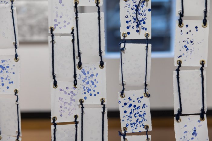 Fatima Naqvi, ‘Blind Faith’ (2025). Blue ink stamped with prayer bead on 99 A7 panels joined together using eyelet rings and blue thread; 94.5cm x 81.4cm. Photograph: Anna Kucera.