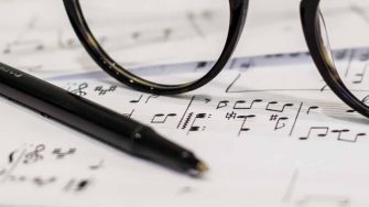 musical notation on a page, with a pen and glasses