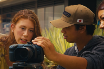 Female student looking at video camera with two other students.