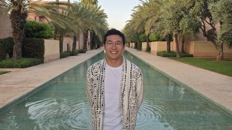 Matthew stands smiling in front of a pool.
