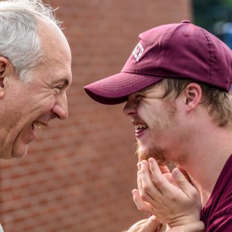 Elderly man embracing student with disability