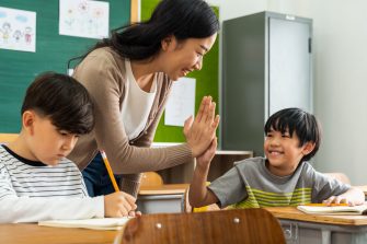 Teacher giving boy high five in school.