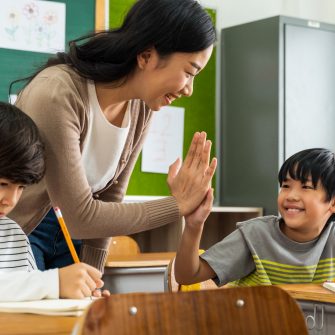 Teacher giving boy high five in school.