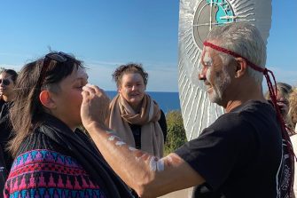 Indigenous man spreading ochre on woman's face