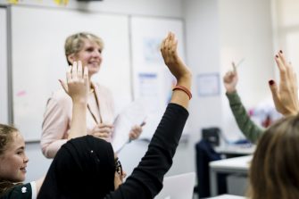 Students with their hands up responding to their teacher