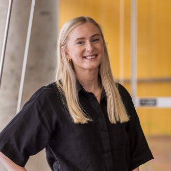 HDR student standing against a yellow background