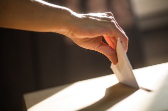 Conceptual image of a person voting, casting a ballot at a polling station, during elections.