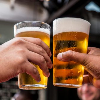 Two hands cheers full beer glasses together