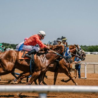 A group of people on horses race on a dirt track