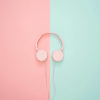 Pink wired headphones on a pink and teal wall