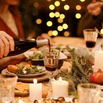A glass of wine is poured into a glass at a Christmas dinner party