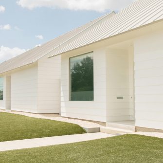 A white house with a single window and manicured lawn