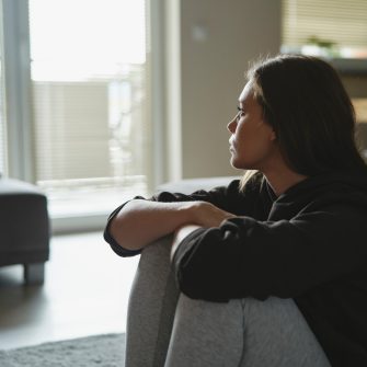 Sad woman sitting on the floor looking out window