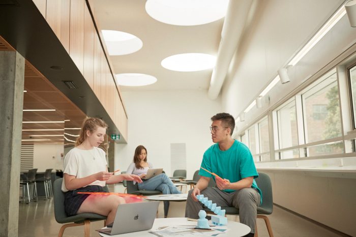 Art and design students discussing work inside the Red Center build enviroment study space.