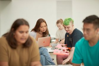 Art and design students discussing work inside the Red Center build enviroment study space.