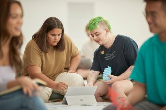 Art and design students discussing work inside the Red Center build enviroment study space.