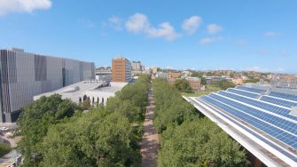 Campus mall walkway aerial shot showing solar panels and green trees lining the main mall