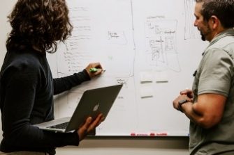 Two people working together with a laptop and a whiteboard