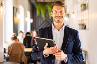 Student holding a book and smiling at the camera