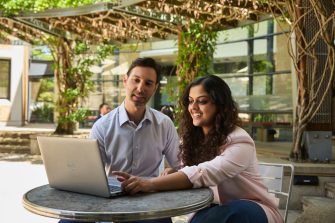 AGSM at UNSW students working together with a laptop outside in the courtyard on campus