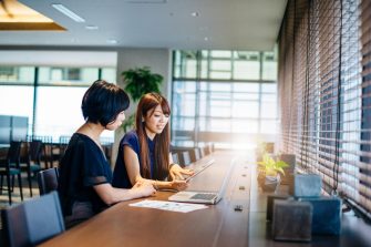 Mature Asian businesswoman in discussion with colleague