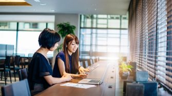 Mature Asian businesswoman in discussion with colleague