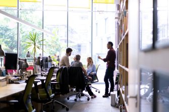 Multi-ethnic business people discussing in office. Male and female professionals are working together at workplace. They are wearing smart casuals.