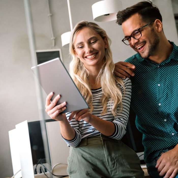Young manager talking with experienced colleague while using computer in office. Colleagues discuss business, financial and marketing projects. Specialists work in diverse startup team.