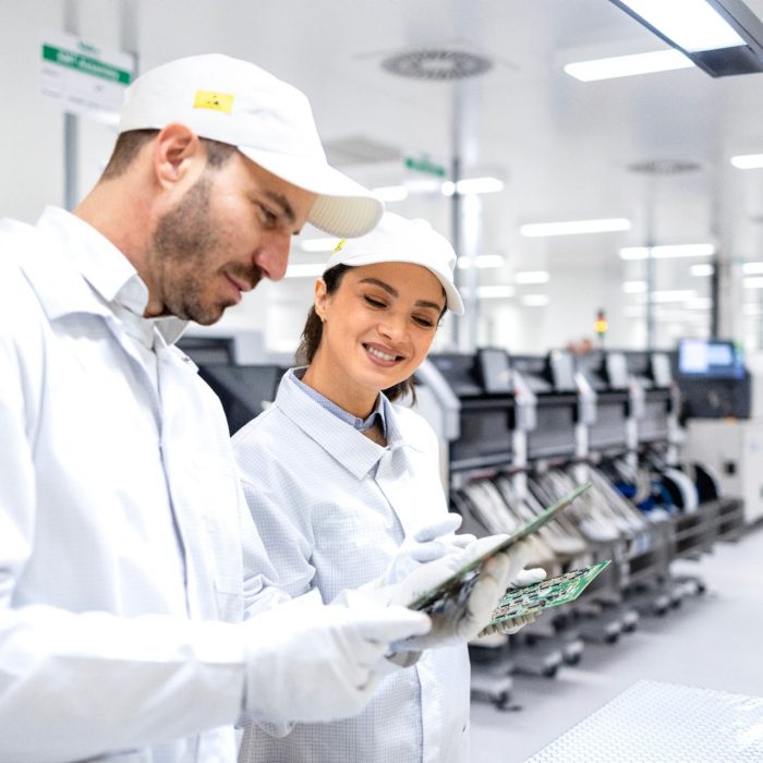 Experienced quality control workers checking electronics components in production factory.