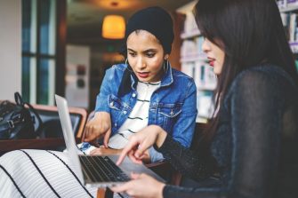 two-women-looking-and-pointing-at-macbook