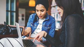 two-women-looking-and-pointing-at-macbook