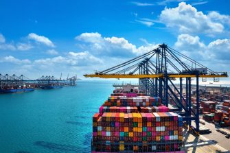 Aerial view of cargo ship and cargo container in harbor.