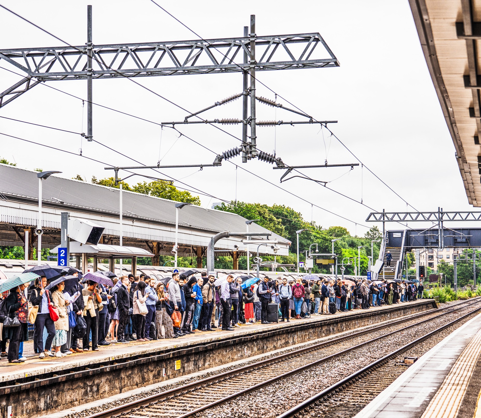 A station platform in Ealing, West London, full of passengers waiting for a train into the city centre.