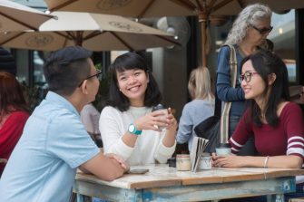 Students sitting at a cafe table smiling
