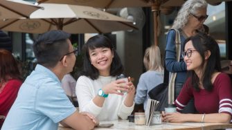 Students sitting at a cafe table smiling