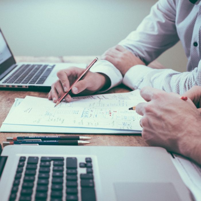 Close up of people working with laptops and papers