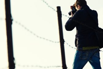 War reporter on the field behind barb wire