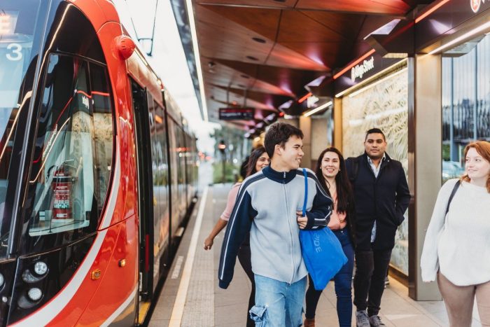 A group of students hop off the light rail at Alinga Street