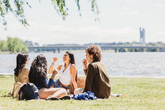 A group of students have a picnic beside Lake Burley Griffin at Bowen Park