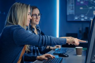 Two Female IT Programers Working on Desktop Computer in Data Center System Control Room. Team of Young Professionals In Software and Hardware Development, Doing Coding