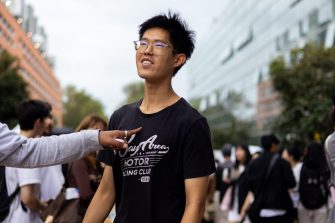 A student points to another student on University Mall. O-Week crowds can be seen in the background.