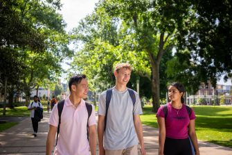 Three students chatting while walking on the Kensington Campus main walkway, University Mall