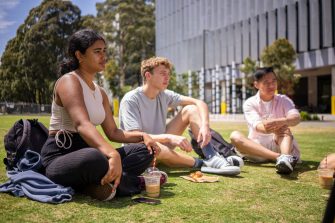 Students chatting and laughing on the grass at Alumni Park on the UNSW Kensington Campus