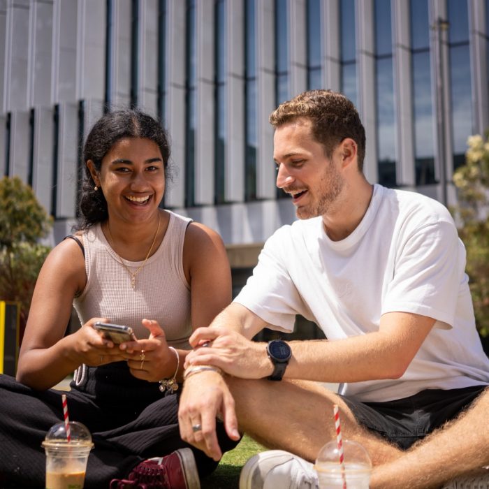 Students chatting and laughing on the grass at Alumni Park on the UNSW Kensington Campus