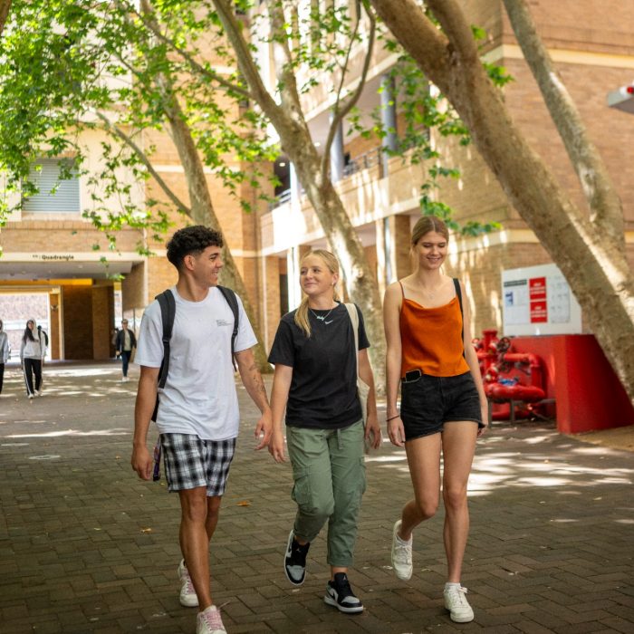 Three students chatting while walking on Kensington Campus