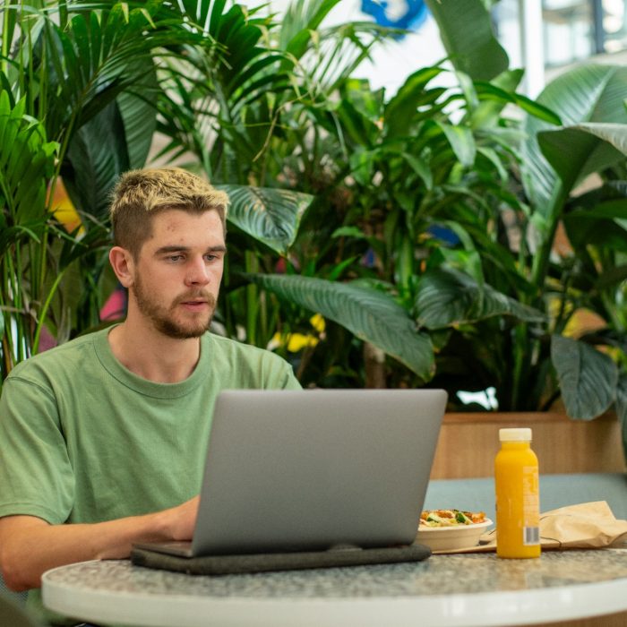 A student sitting at their laptop while eating lunch on Kensington Campus
