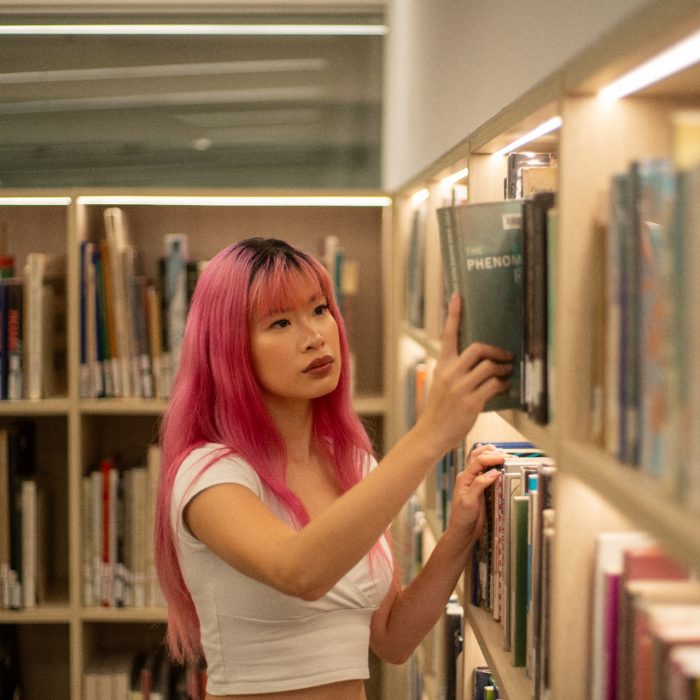 A student browsing the bookshelves in the Paddington Campus library