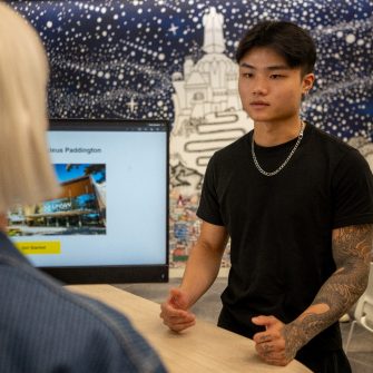 A student chatting to a staff member in the student hub on Paddington Campus